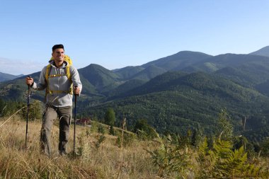 Sırt çantalı turist ve yürüyüş direkleri dağlarda yürüyüş yapıyor, yazı için yer var.
