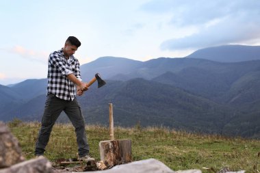 Dağlarda odun kesen baltalı yakışıklı bir adam.