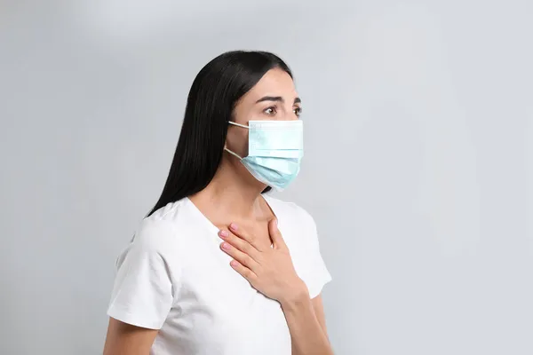 Young Woman Protective Mask Suffering Breathing Problem Light Background — Stock Photo, Image