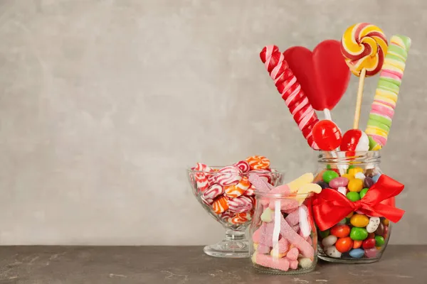 Üvegek Különböző Ízletes Cukorkák Szürke Asztalon Hely Szövegnek — Stock Fotó