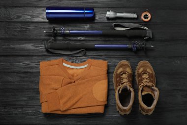 Siyah ahşap zemin üzerinde yürüyüş direkleri ve diğer yürüyüş ekipmanları ile düz bileşim yatıyordu