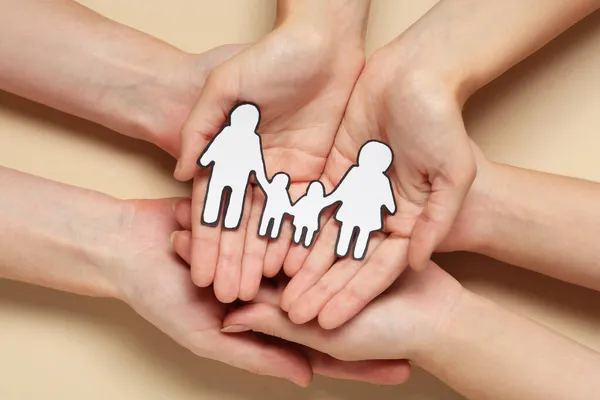 People holding paper family cutout on beige background, top view