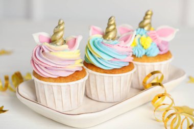 Tatlı tatlı tek boynuzlu at kekleri ve beyaz masada şenlikli bir dekor.