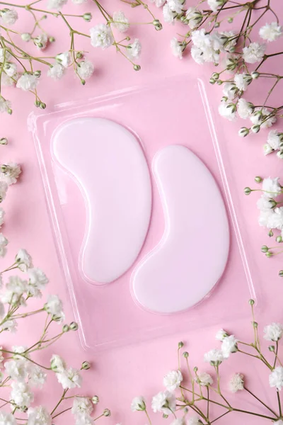 ライトピンクの背景に目のパッチや花の下にパッケージ フラットレイアウト 化粧品 — ストック写真