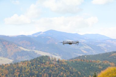 Modern insansız hava aracı sonbahar günü dağlarda uçuyor.