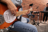 Muž hrající na elektrickou kytaru při zkoušce ve studiu, detailní záběr. Trénink hudební kapely