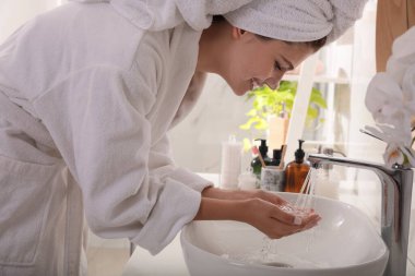 Güzel genç kız banyoda temizleyici köpükle yüzünü yıkıyor. Cilt bakımı kozmetik