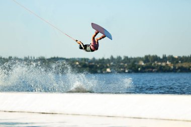 Genç wakeboardcu nehir üzerinde numara yapıyor. Aşırı su sporu