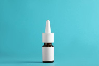 Açık mavi arka planda bir şişe burun spreyi.