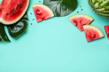 Lezzetli olgun karpuz ve turkuaz arka planda tropikal yapraklar. Metin için boşluk