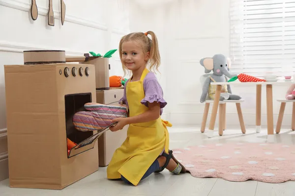 Маленькая Девочка Играет Игрушечной Картонной Печью Дома — стоковое фото