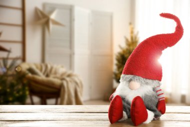 Odasındaki ahşap masada süslü süslemeleri olan komik noel cücesi. Metin için boşluk