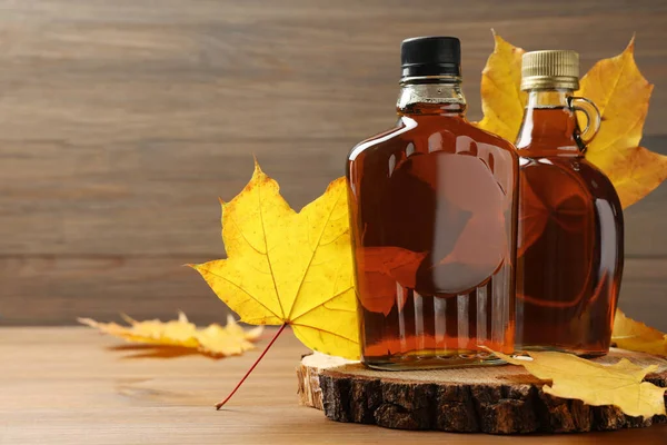 Bottles Tasty Maple Syrup Dry Leaves Wooden Table Space Text — Stock Photo, Image