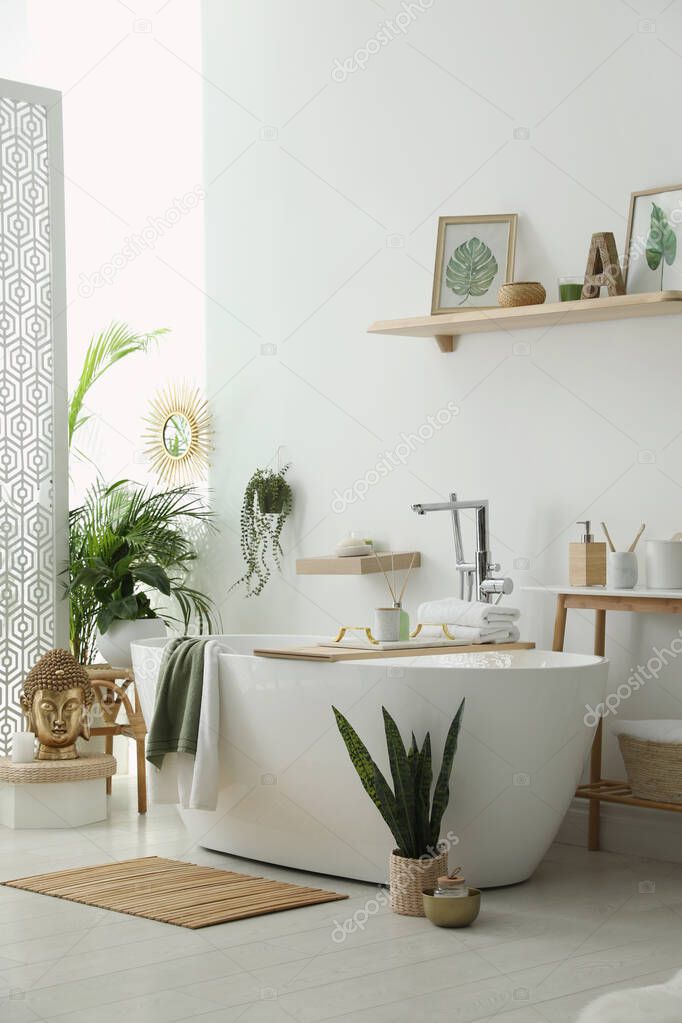 Stylish bathroom interior with modern tub, houseplants and beautiful decor. Home design