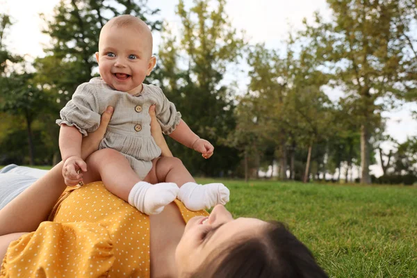 幸せな母ともにかわいいです赤ちゃん嘘で緑の草で公園 — ストック写真
