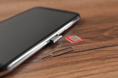 Cep telefonu, SIM kart ve fırlatma aracı ahşap masa üzerinde, yakın plan