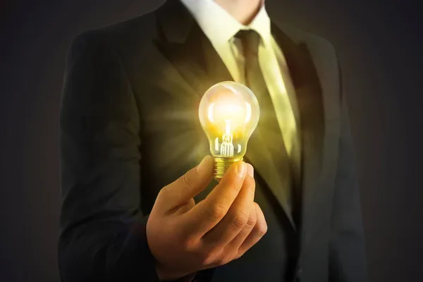 あなたの考えを上げなさい 暗い背景に電球を持っているビジネスマン クローズアップ — ストック写真