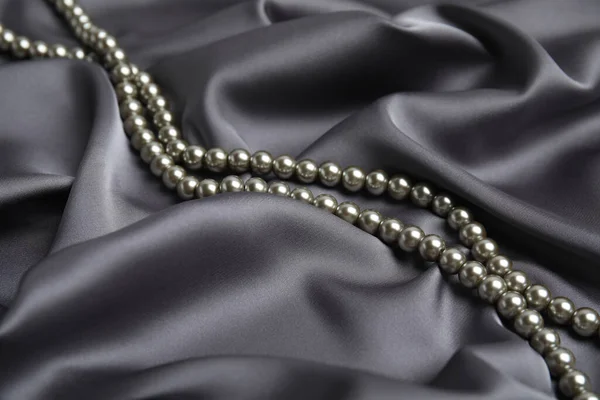 精美的银珠镶嵌在精致的灰色丝绸上 — 图库照片