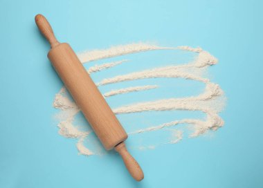 Açık mavi arka planda ahşap oklu iğne ve un, üst manzara. Metin için boşluk