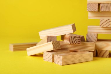 Tahta Jenga blokları sarı arka planda, yakın plan