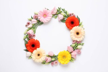 Güzel çiçeklerden yapılmış çelenk ve beyaz arka planda yeşil yapraklar, düz bir zemin. Metin için boşluk