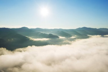 Güneşli bir günde bulutlarla kaplı güzel dağların hava manzarası. Drone fotoğrafçılığı
