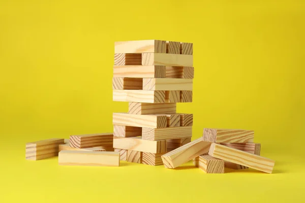 stock image Jenga tower and wooden blocks on yellow background