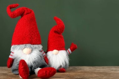 Ahşap masada yeşil arka planda sevimli noel cüceleri. Metin için boşluk