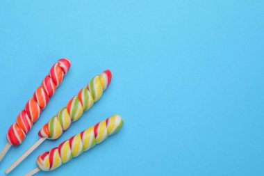 Açık mavi arka planda tatlı lolipoplar, düz uzanmış. Metin için boşluk