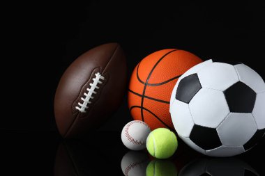 Siyah ayna yüzeyinde farklı spor topları kümesi