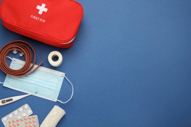 Mavi arkaplan üzerinde ilk yardım çantasıyla düz konum, metin için boşluk