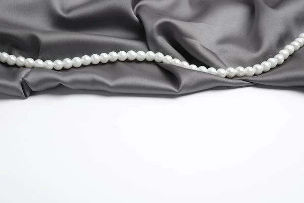 白色背景上美丽的珍珠和灰色丝绸 图库图片