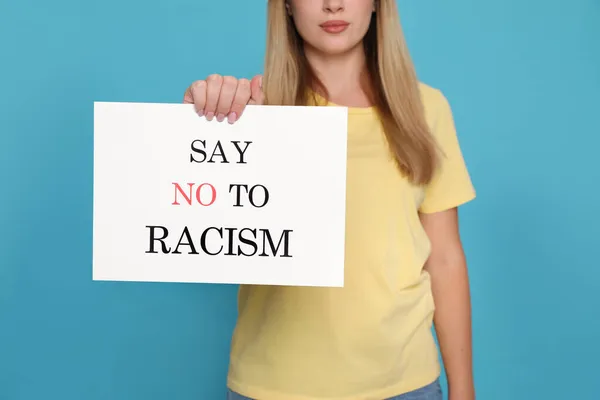 年轻女子手持标语 用浅蓝色背景和特写镜头向种族主义说不 — 图库照片