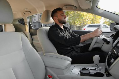 Modern arabada oturan yakışıklı genç sürücü.