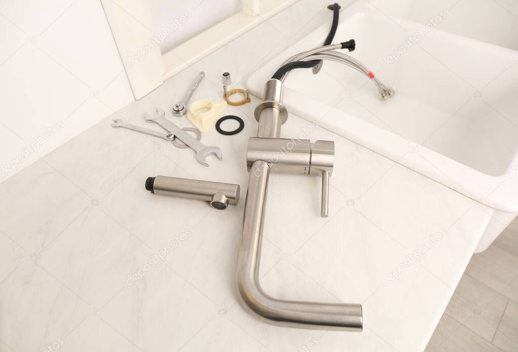 Plumber's tools and water tap ready for installation near sink on countertop in kitchen