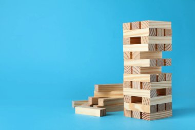 Jenga kulesi ve açık mavi arkaplanda tahta bloklar, metin için boşluk