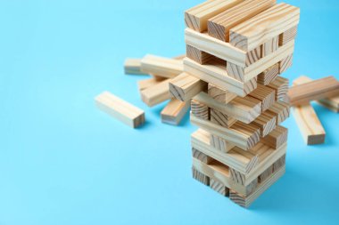 Jenga kulesi ve açık mavi arkaplanda tahta bloklar, metin için boşluk