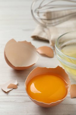 Kırık tavuk sarısı ve yumurta kabuğu ahşap masada, yakın plan.