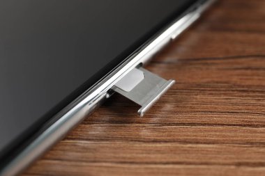 Ahşap masadaki Sim kartlı cep telefonu, yakın plan.