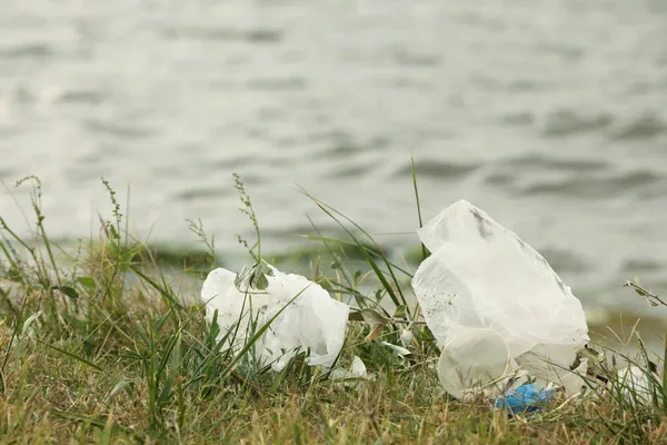 川の近くの芝生に撒かれたプラスチックごみ — ストック写真