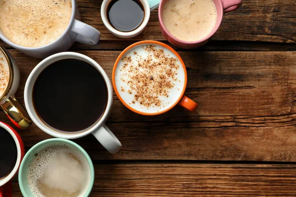 Bir sürü farklı kahve fincanı ahşap masada, düz yerde. Metin için boşluk