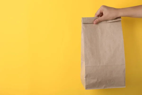 Woman Holding Paper Bag Yellow Background Closeup Space Text — Stock Photo, Image