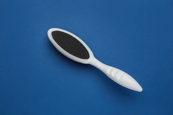 White foot file on blue background, top view. Pedicure tool