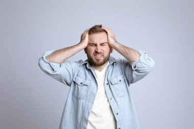 Genç adam ışık arka plan üzerinde baş ağrısı muzdarip