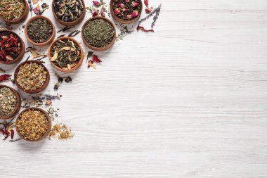 Düz kompozisyon ve beyaz ahşap masa üzerinde farklı kuru çaylar. Metin için boşluk