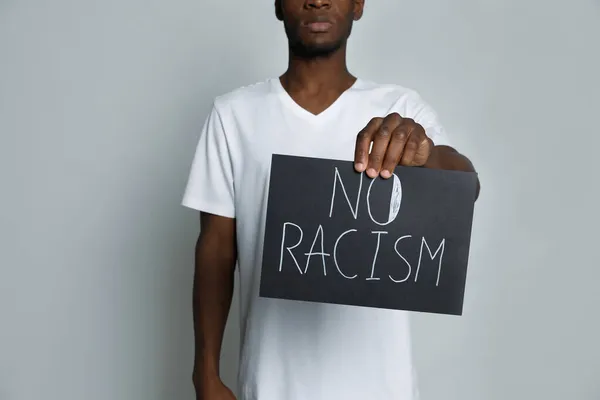 African American Man Holding Sign Phrase Racism Grey Background Closeup — Stock Photo, Image