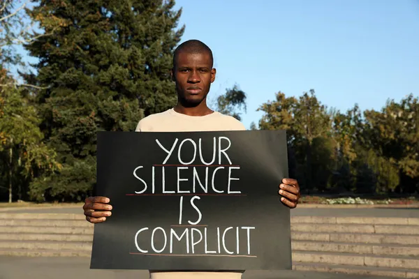 非洲裔美国人手持标语 你的沉默在室外是同谋 种族主义概念 — 图库照片