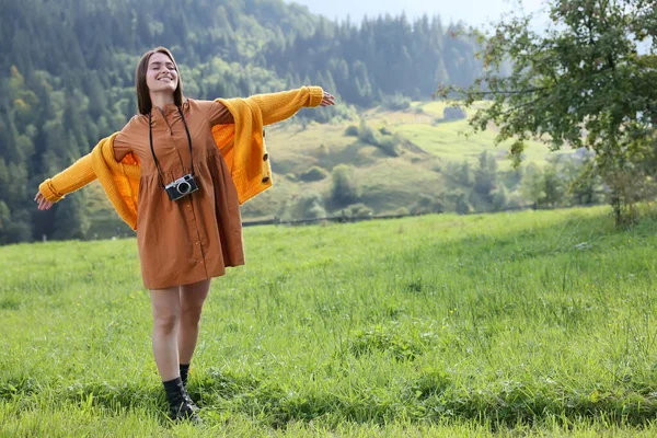 山の中の牧草地で踊るカメラを持つ幸せな女性 — ストック写真