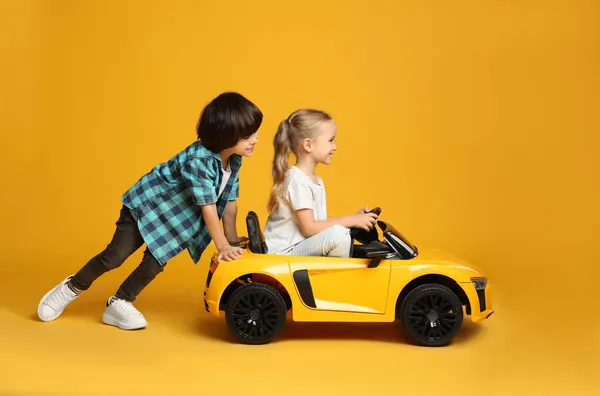 Cute Boy Pushing Children Electric Toy Car Little Girl Yellow — Stock Photo, Image