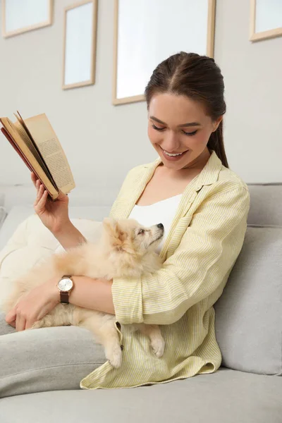 Glad Ung Kvinna Läser Bok Med Söt Hund Soffa Vardagsrummet — Stockfoto
